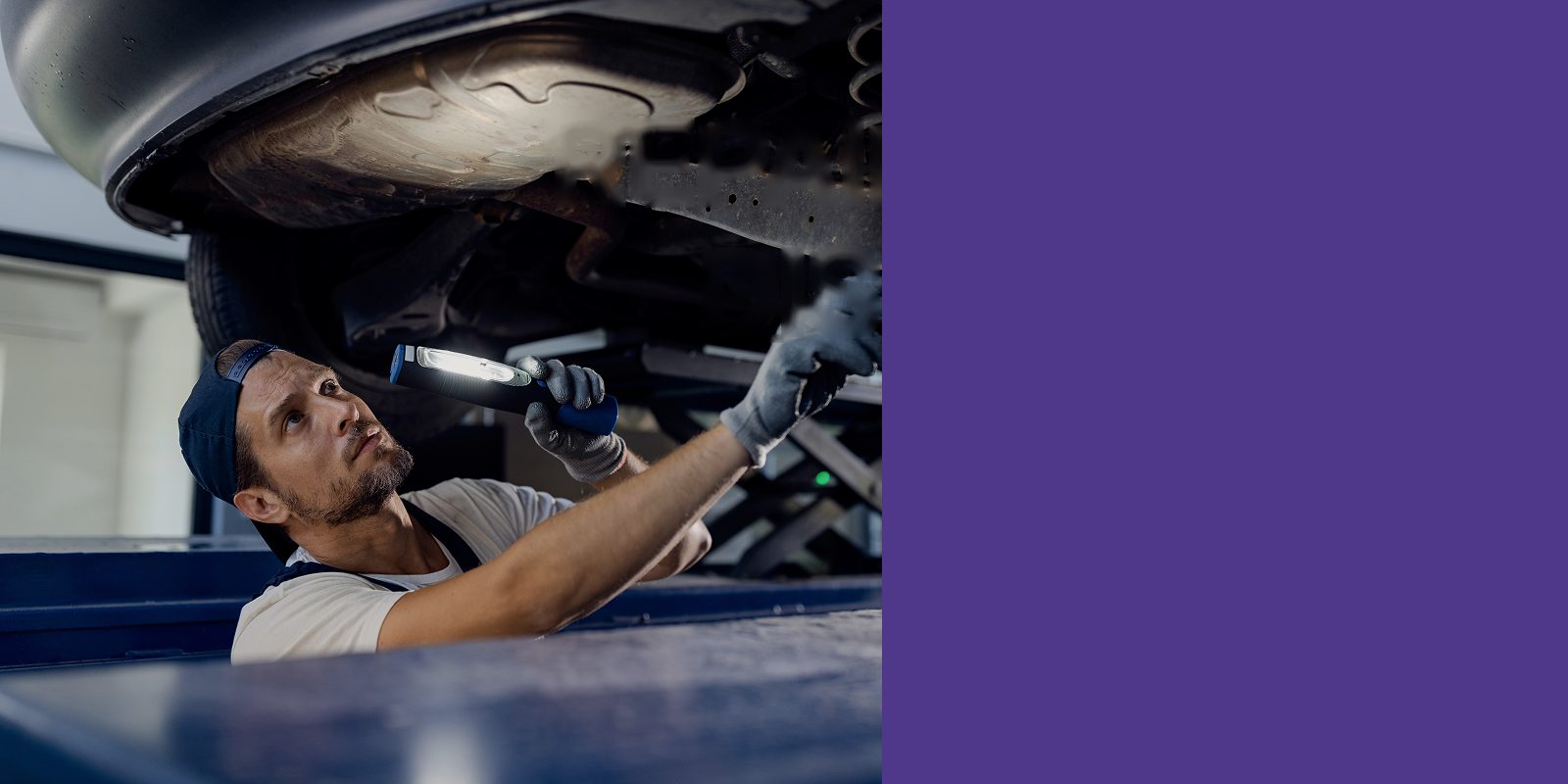 Mechanic inspecting a car from below with a work light